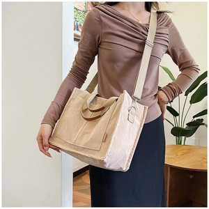 Detail of beige corduroy tote bag showing vertical ribs and detachable strap on model