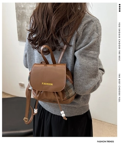 Detail of contrast plaid stitching and pearl drawstring on brown leather backpack