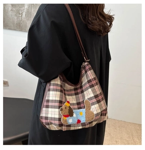 Detail of checkered hobo bag with a plush puppy patch and adjustable leather strap