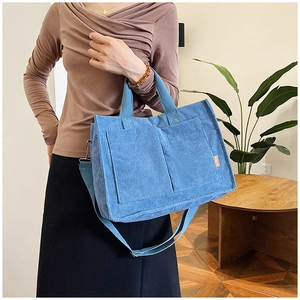 Dettaglio borsa tote in velluto a coste blu con due tasche frontali e etichetta Fashion