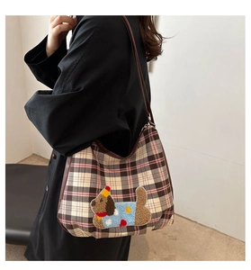 Detailed close-up of a vintage plaid crossbody bag with an embroidered cartoon dog patch