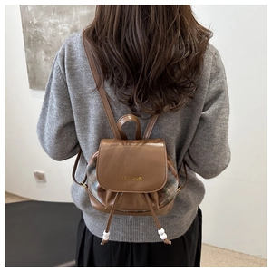 Detail of checkered patchwork mini backpack showing the fashion gold logo and drawstring