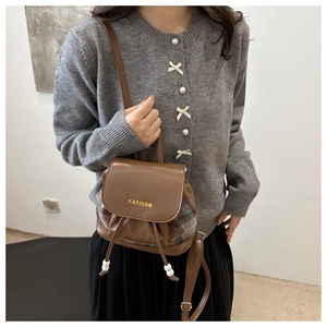 Detailed view of brown leather and plaid stitching on mini backpack with drawstring