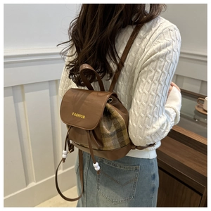 Close-up of a plaid and leather mini backpack with a drawstring and fashion flap detail