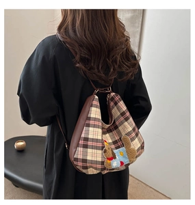 Detail of checkered tote bag with plush dog embroidery and brown leather side panel