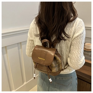 Detail view of mini plaid patchwork backpack with yellow Fashion lettering and drawstring