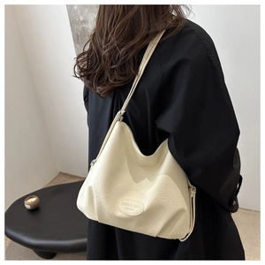 Detail of cream-white leather hobo bag showing pebbled texture and ZEKE & NAG logo patch