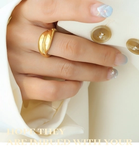 Detail showing a layered 18K gold plated ring worn on the finger with a chic blazer