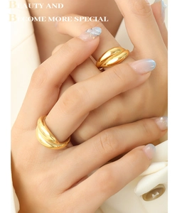 Macro detail of gold-plated croissant twisted rings with polished finish on model's hand