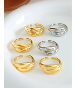 Detailed view of six gold and silver stackable twisted metal rings in a ceramic tray