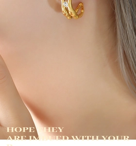 Close-up of vintage golden twisted earrings featuring a single inlaid zircon gemstone