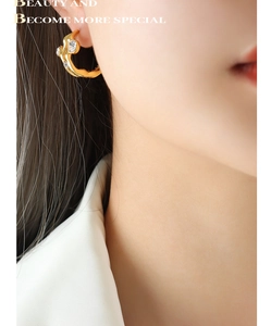Close-up of gold wavy hoop earrings with inlaid cubic zirconia on female model