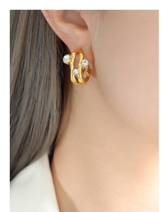 Close-up of gold lava texture hoop earrings with zircon stones on female model