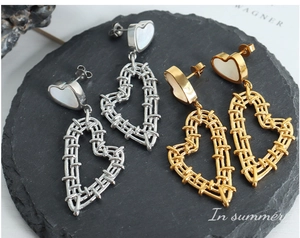 Detailed macro view of heart-shaped earrings with shell inlay and hollow woven metal design