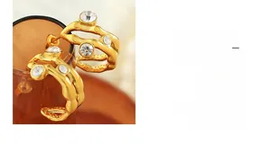 Detail of gold layered wave earrings with cubic zirconia set on an amber glass rim