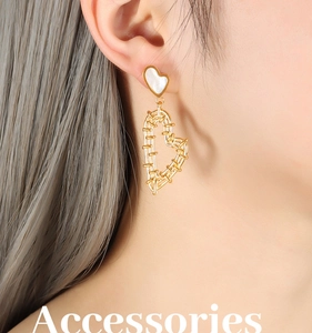 Detail of elegant gold-plated heart drop earrings featuring a white shell heart inlay