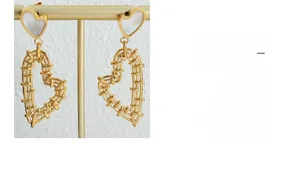 Detail of vintage gold heart earrings with white shell inlay and hollow woven textures