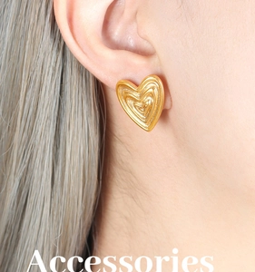 Detailed close-up of gold-plated heart stud earrings with concentric linear texture