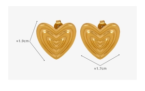 Macro view of gold heart earrings showing textured wave patterns and dimensions