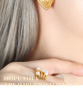 Close-up of 18K gold heart earrings and pearl ring with elegant matte relief texture
