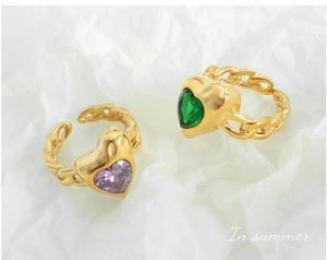 Close-up of gold twisted rings with heart-shaped purple and green crystal gemstones
