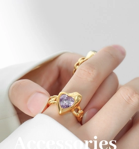 Detailed shot of a gold chain ring with a purple heart-shaped crystal on a hand