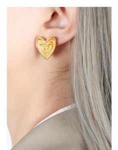 Macro shot of gold-plated titanium steel heart studs with textured concentric circles