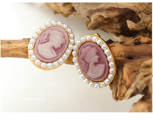 Macro shot of vintage cameo earrings with pink portrait relief and pearl borders