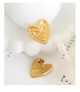 Detail shot of 18K gold heart earrings featuring concentric embossed patterns and texture