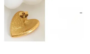 Detail of 14K gold heart stud earring back with sunburst texture and butterfly clasp