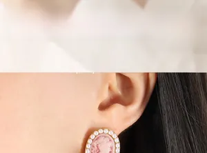 Close-up of vintage pink cameo earrings with pearls shown on model ear
