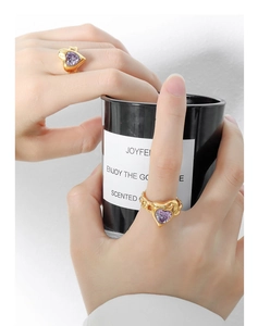 Detail of gold-plated rings featuring purple heart-shaped zircons on model hand
