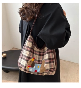 Detail of plaid tote bag with cute puppy patch and party hat worn by model