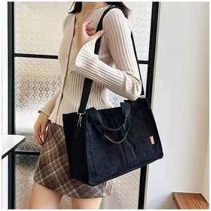 Dettaglio della borsa tote in velluto a coste nero con etichetta fashion e materiale