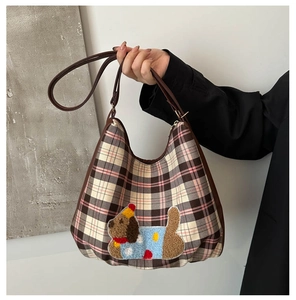 Close-up of checkered hobo bag featuring teddy dog embroidery and brown leather strap