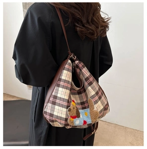 Detail of checkered tote bag with cartoon dog patch and brown leather straps