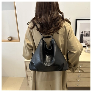 Rear view of model wearing a black large-capacity tote bag in a minimalist room