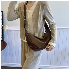 Close-up of brown PU leather crescent bag featuring adjustable shoulder strap and metal buckle