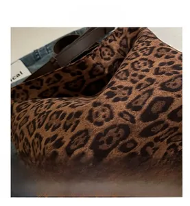 Close-up of leopard print fabric texture and dark brown leather strap on tote bag