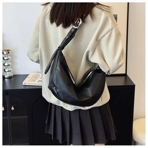 Minimalist black crescent moon shoulder bag in soft PU leather worn by a model