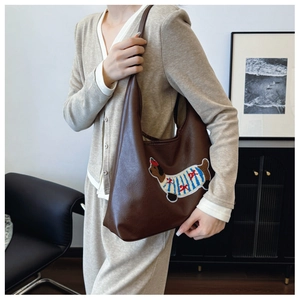 Dettaglio della borsa in pelle marrone scuro con ricamo di bassotto in maglia a righe