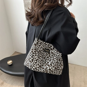 Borsa tote leopardata con manici in pelle nera indossata da una modella per lo stile