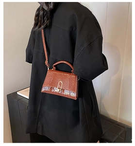 Détail d'un sac à main marron foncé motif crocodile avec fermoir en métal doré en forme de U
