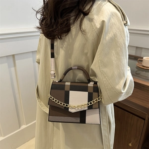 Chic geometric plaid flap bag with gold chain strap worn with a stylish beige coat