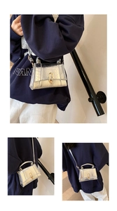 Détail macro du mini sac argenté avec motif crocodile et boucle de verrouillage en métal doré