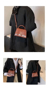 Détail du sac à main marron motif crocodile avec boucle dorée en U et texture en cuir poli