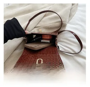 Vue intérieure du sac bandoulière marron motif crocodile montrant l'espace pour téléphone et maquillage