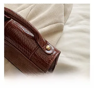 Gros plan sur cuir marron gaufré crocodile avec des clous en métal doré poli