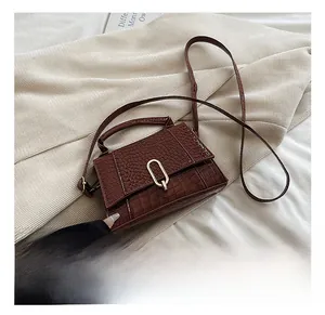 Détail d'un sac à main marron motif crocodile avec boucle en métal doré élégante
