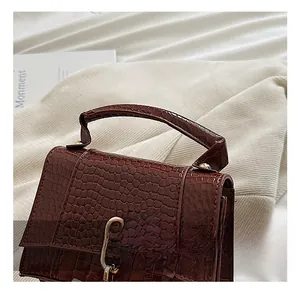 Gros plan détaillé de la texture crocodile marron foncé et du fermoir doré sur le sac